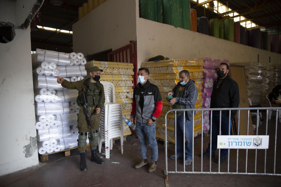 Palestinian laborers who work in Israeli settlements line up to receive second dose of the Moderna COVID-19 vaccine in the Barkan industrial area near of the West Bank town of Nablus, Sunday, April 11, 2021. (AP Photo/Majdi Mohammed)