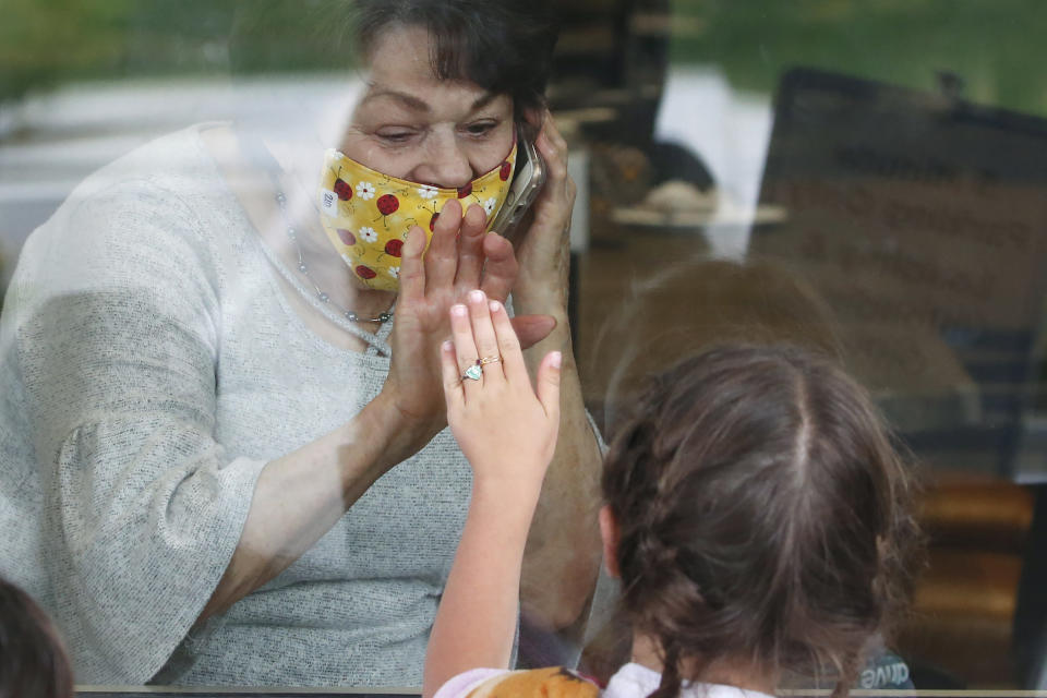 FILE - In this April 23, 2020, file photo, Raelene Critchlow, 86, receives a visit from her great-grandchild Camille Carter, 6, at Creekside Senior Living in Bountiful, Utah. Window visits help seniors connect to families despite coronavirus restrictions. (AP Photo/Rick Bowmer, File)