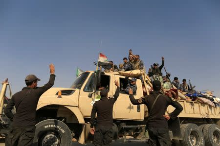 Iraqi special forces soldiers wave to a group of newly trained police formed from people displaced by Islamic State militants, as the group sits on a truck bound for the frontline of the Mosul offensive against Islamic State, near Bazgirtan, Iraq, October 26, 2016. REUTERS/Zohra Bensemra