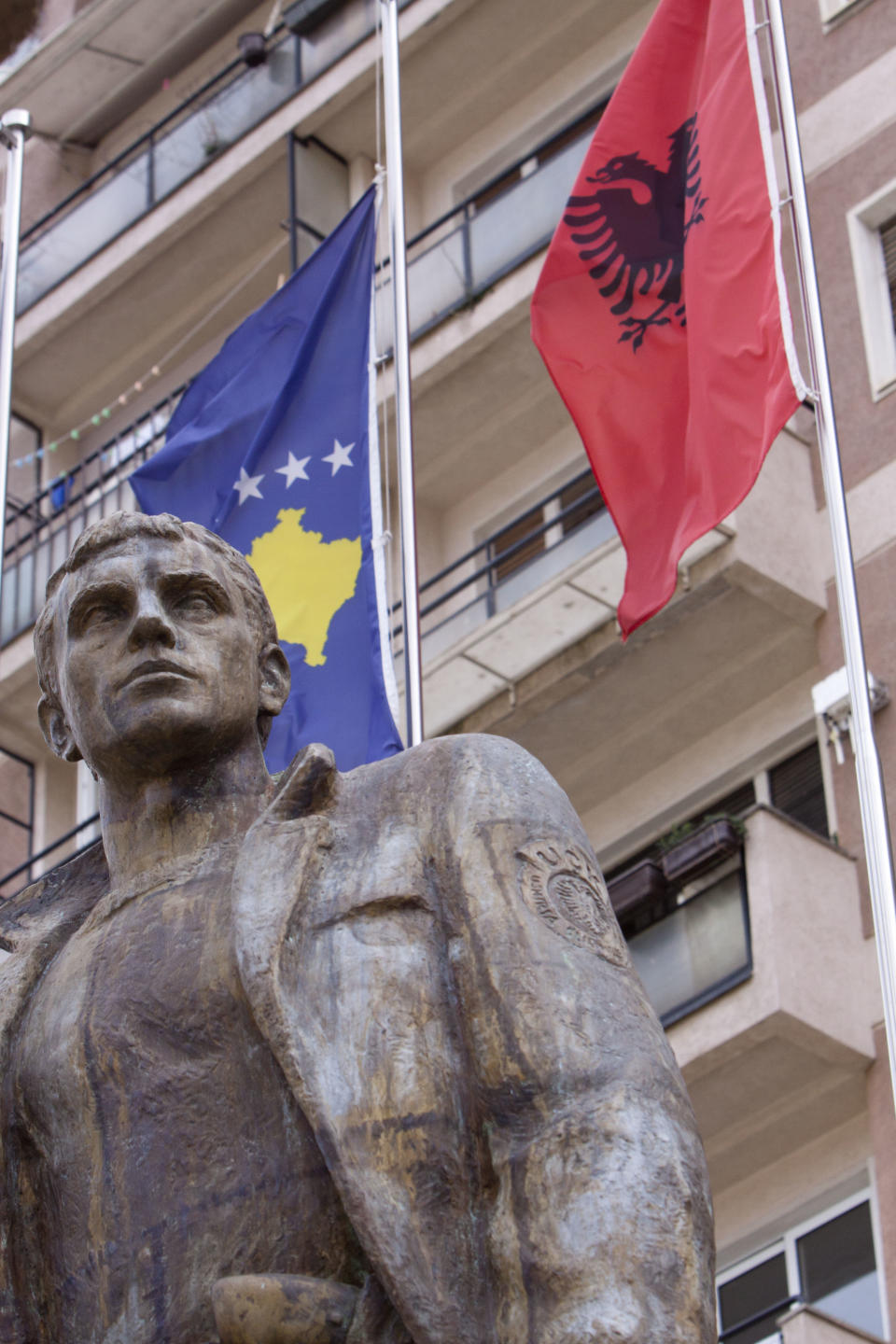 Kosovo and Albanian flags tower over a bronze statue, put up in memory of a Kosovo Liberation Army member in Kosovo capital Pristina on Friday Apr. 4, 2014. Former guerrillas have dismissed EU plans to set up an international tribunal to try former members of the Kosovo Liberation Army as anti Albanian. (AP Photo/Visar Kryeziu)