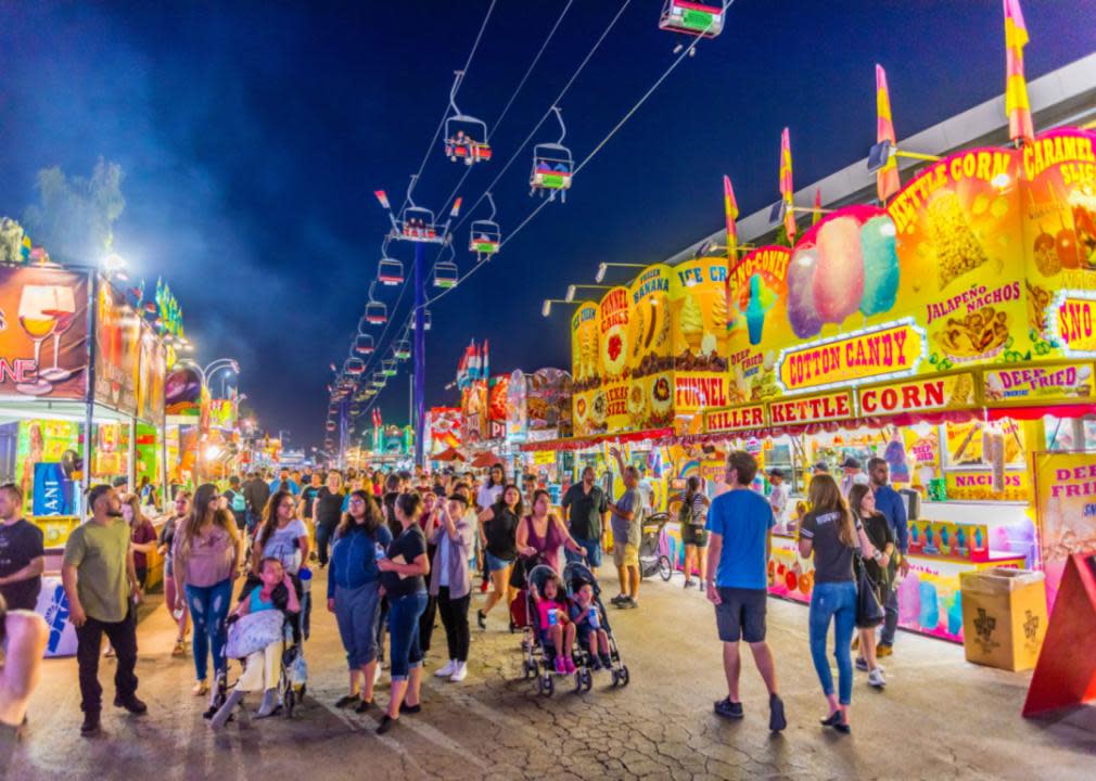 Crowds of families at the Arizona State Fair surrounded by colorful lights, games and concession stands.