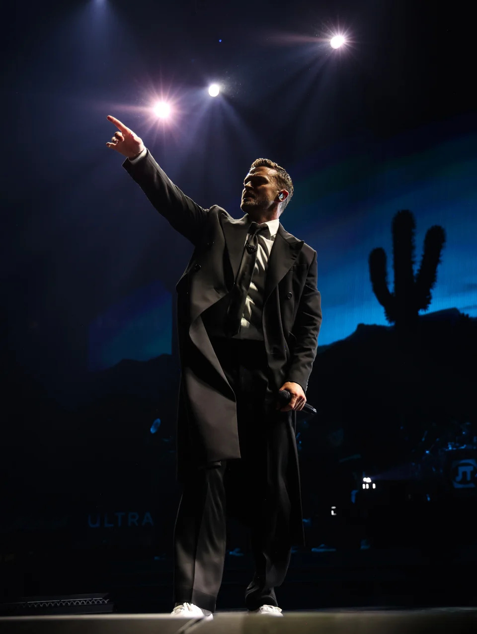 Justin Timberlake pointing with his left hand while holding a mic in his right, onstage at Madison Square Garden in NYC. 