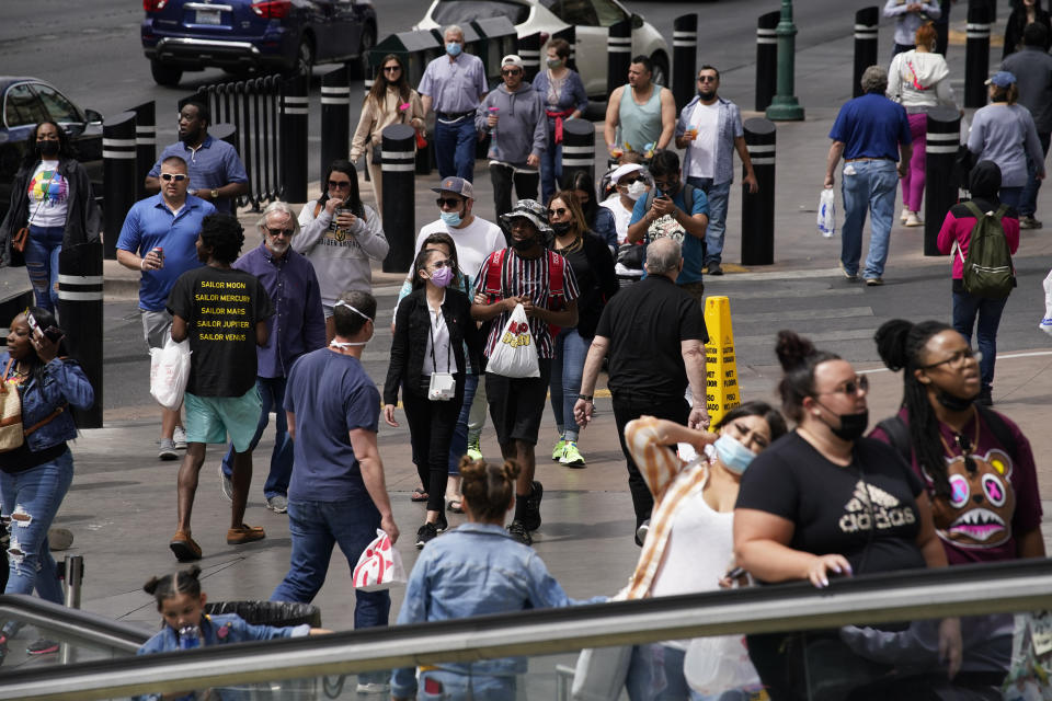 Masked and unmasked pedestrians walk along the Las Vegas Strip, Tuesday, April 27, 2021, in Las Vegas. The Centers for Disease Control and Prevention eased its guidelines Tuesday on the wearing of masks outdoors, saying fully vaccinated Americans don't need to cover their faces anymore unless they are in a big crowd of strangers.(AP Photo/John Locher)