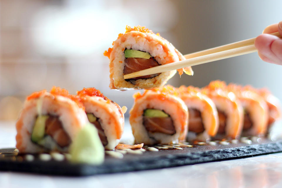 A woman eats sushi at a table.