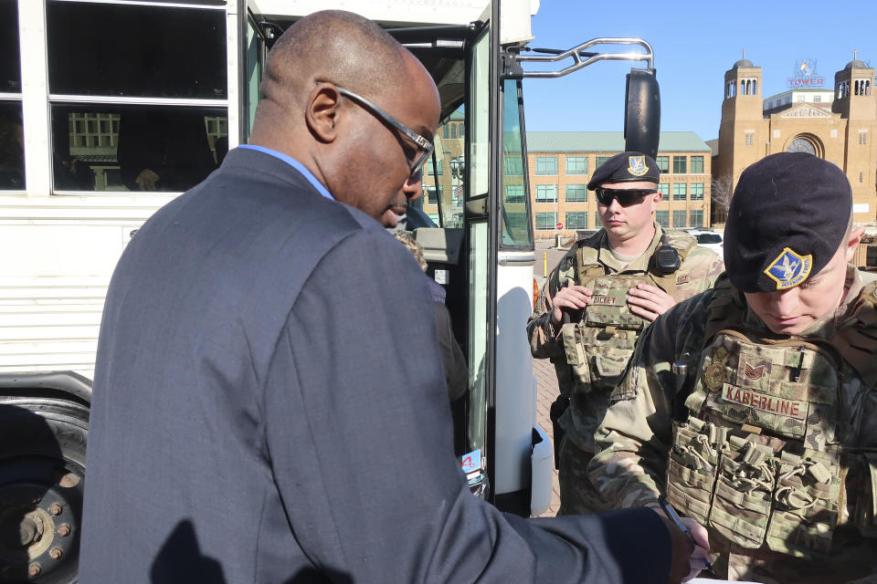 Kansas state Rep. K.C. Ohaebosim, left, D-Wichita, has his driver's license checked by military personnel before boarding a National Guard bus to a Department of Homeland Security briefing, Tuesday, Jan. 14, 2020, outside the Statehouse in Topeka, Kan. Lawmakers said the unclassified briefing dealt with potential foreign attempts to gain information about Kansas business and agricultural interests. (AP Photo/John Hanna)