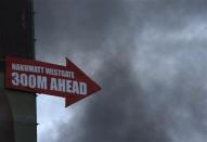 A sign pointing to the direction of Westgate shopping centre is pictured as smoke rises in the vicinity in Nairobi September 23, 2013. REUTERS/Karel Prinsloo