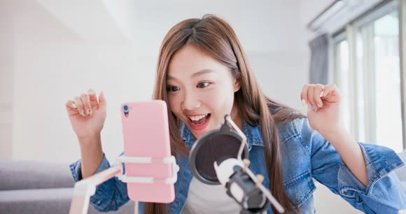 A young woman records a video on her smartphone.