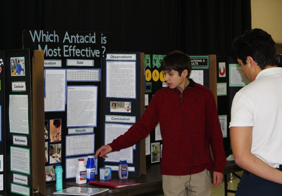 Eighth-grader Nicholas Forsythe explains his science project to a STEM Fair attendee, Thursday, Jan. 18, 2024, at St. James Lutheran School. Forsythe received a first place ribbon and the "Champion Award" for his work.