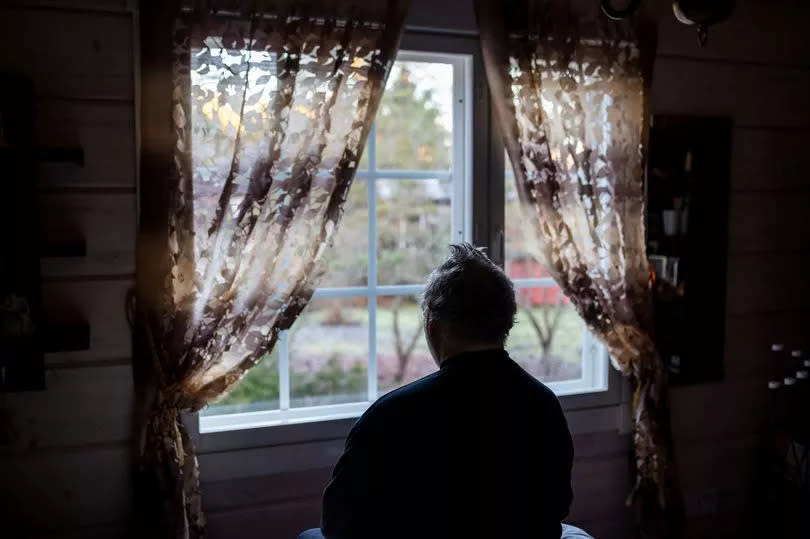 Senior man sitting alone at bedroom. Male portrait at home at morning.