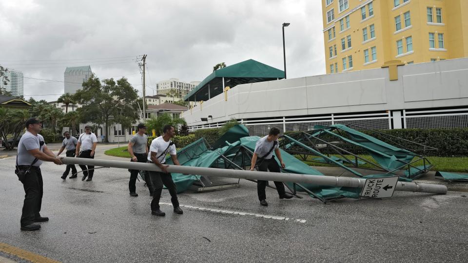 Members of the Tampa Fire Rescue Dept., remove a street pole after large awnings from an apartment building blew off from winds associated with Hurricane Idalia Wednesday, Aug. 30, 2023, in Tampa, Fla. Idalia made landfall earlier this morning along the Big Bend of the state. (AP Photo/Chris O'Meara)