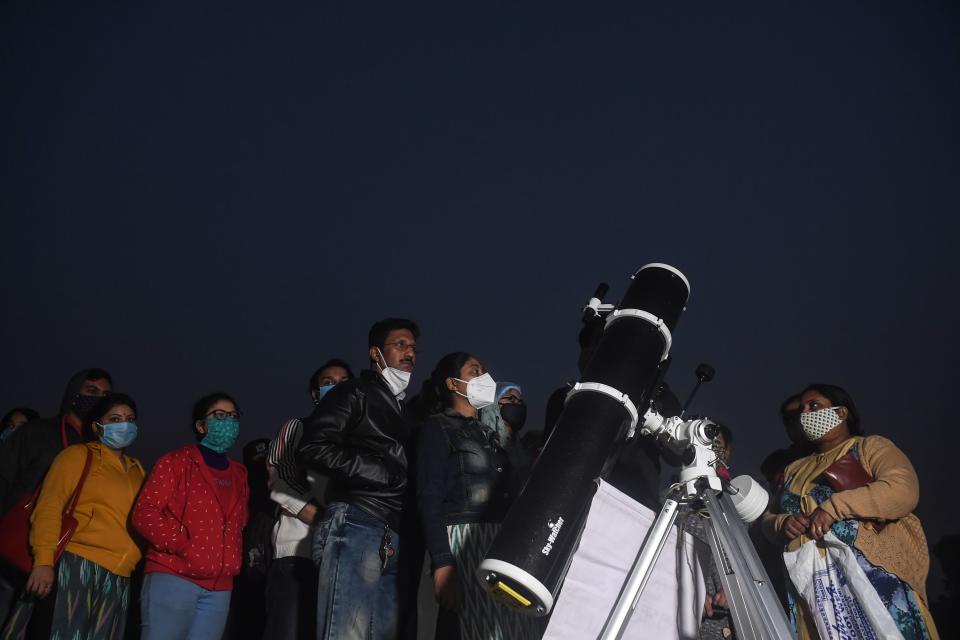 People stand in a queue to see a 'great conjunction' of Jupiter and Saturn at the Maidan area in Kolkata on December 21, 2020. (Photo by Dibyangshu SARKAR / AFP) (Photo by DIBYANGSHU SARKAR/AFP via Getty Images)