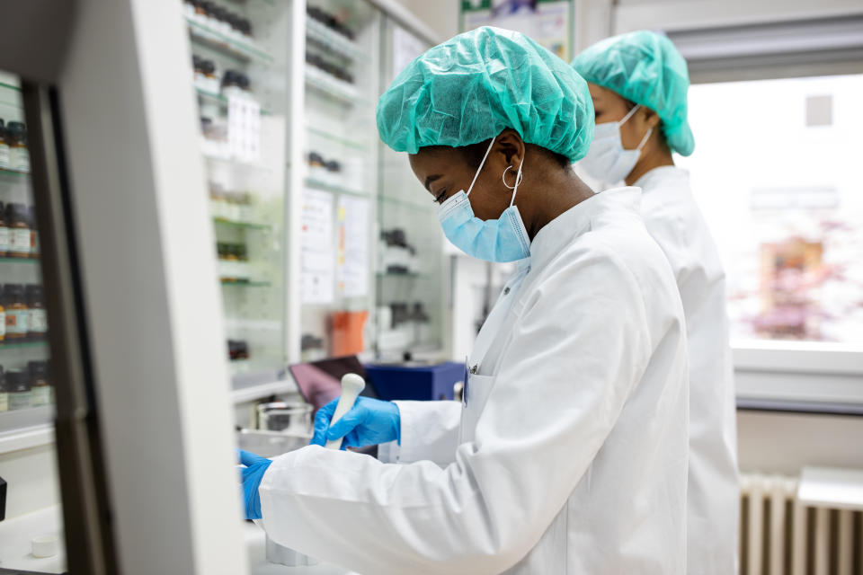 Two female scientists making medicine at a laboratory. Doctors working together at pharmacy lab wearing protective work wear.