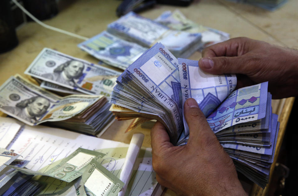 FILE - In this August 20, 2018 file photo, a man counts Lebanese pounds at an exchange shop, in Beirut, Lebanon. The Lebanese pound has hit a record low against the dollar on the black market as the country's political crisis deepens and foreign currency reserves dwindle further. The dollar was trading at 9,975 Lebanese pounds on Tuesday. (AP Photo/Hussein Malla, File)