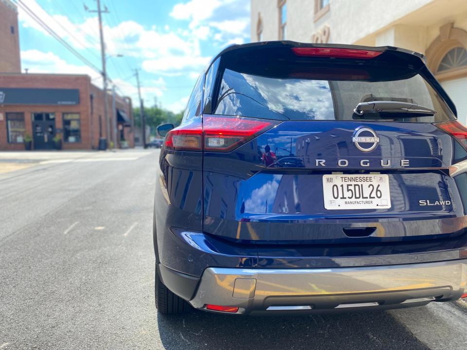 The rear end of a blue 2024 Nissan Rogue SL SUV parked on the side of a street.