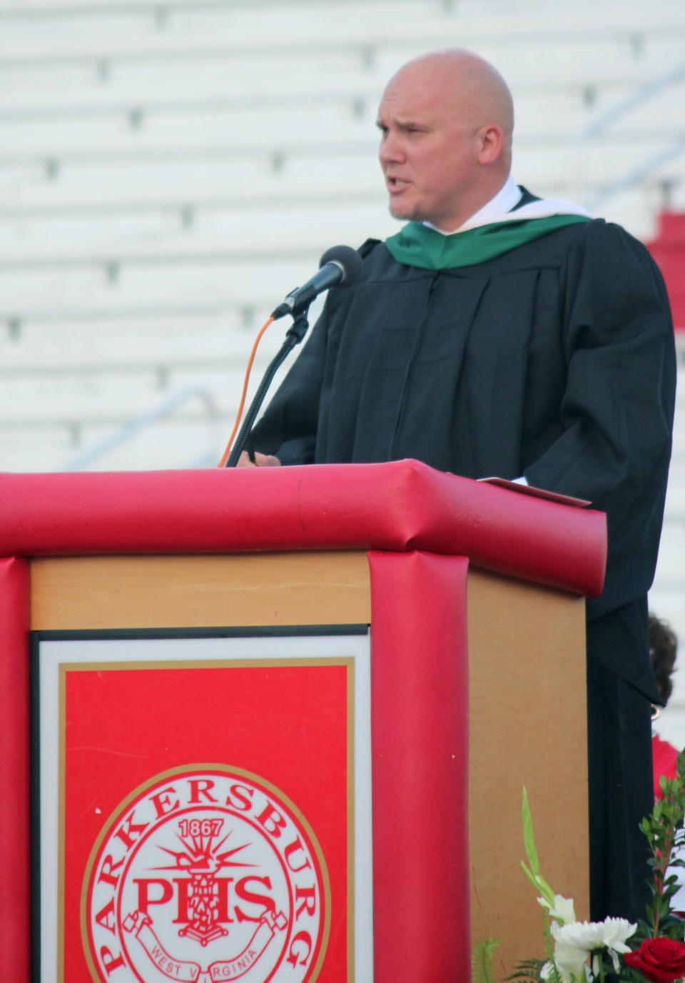 In this May 23, 2019 photo, Principal Kenny DeMoss gives closing remarks during Parkersburg High School’s 2019 graduation ceremony, in Parkersburg, W.Va. The West Virginia principal accused of plagiarizing Ashton Kutcher in the address to his school’s graduating class says he didn’t mean to use someone else’s work. DeMoss has issued a statement saying he should have cited his sources in the speech, but asserted the ideas were his own. (Michael Erb/News and Sentinel via AP)