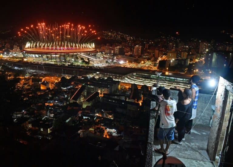 People watch fireworks exploding over the Maracana Stadium, from a terrace in the favela Mangueira in Rio de Janeiro on August 5, 2016