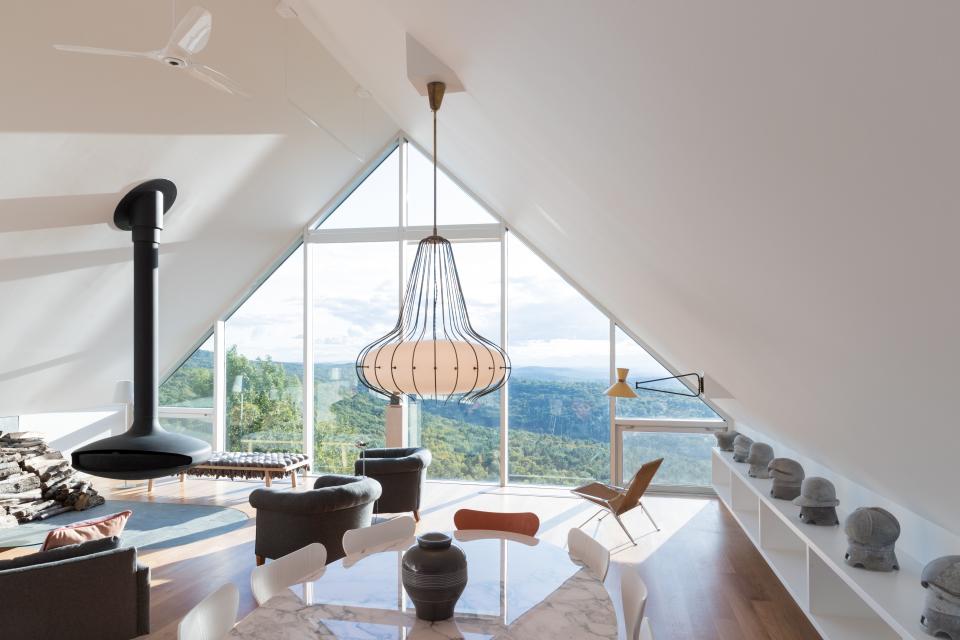 In the living area, an Angelo Lelli pendant hangs over an Eero Saarinen dining table for Knoll with chairs by Arne Jacobsen for Fritz Hansen; the suspended fireplace is by Atelier Dominique Imbert.