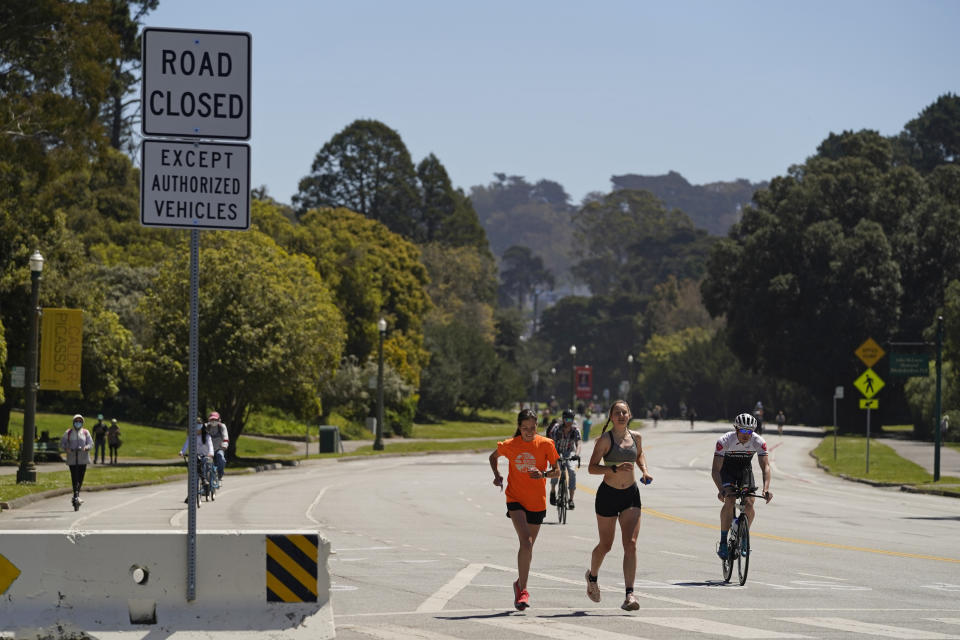 Joggers and cyclists make their way along car-free John F. Kennedy Drive in Golden Gate Park, Wednesday, April 28, 2021, in San Francisco. At the start of the pandemic, San Francisco closed off parts of a major beachfront highway and Golden Gate Park to cars so that people had a safe place to run and ride bikes. Open space advocates want to keep those areas car-free as part of a bold reimagining of how U.S. cities look. But opponents decry the continued closures as elitist, unsafe and nonsensical now that the pandemic is over and people need to drive again. (AP Photo/Eric Risberg)