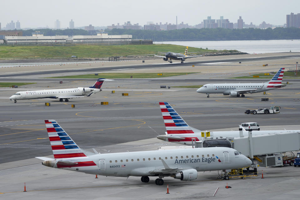 An airplane lands, top, as other line up for takeoff, center, and others are parked at the gate of Terminal B at LaGuardia Airport, Tuesday, June 27, 2023, in New York. Travelers waited out widespread delays at U.S. airports on Tuesday, an ominous sign heading into the long July 4 holiday weekend, which is shaping up as the biggest test yet for airlines that are struggling to keep up with surging numbers of passengers. (AP Photo/Mary Altaffer)