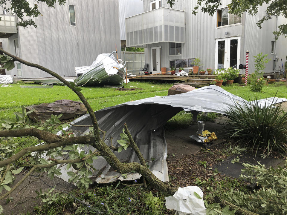 Twisted sheet metal and other damage from a possible tornado sit in a yard after heavy storms moved through the area Tuesday night in the Uptown section of New Orleans, Wednesday, May 12, 2021. (AP Photo/Kevin McGill)