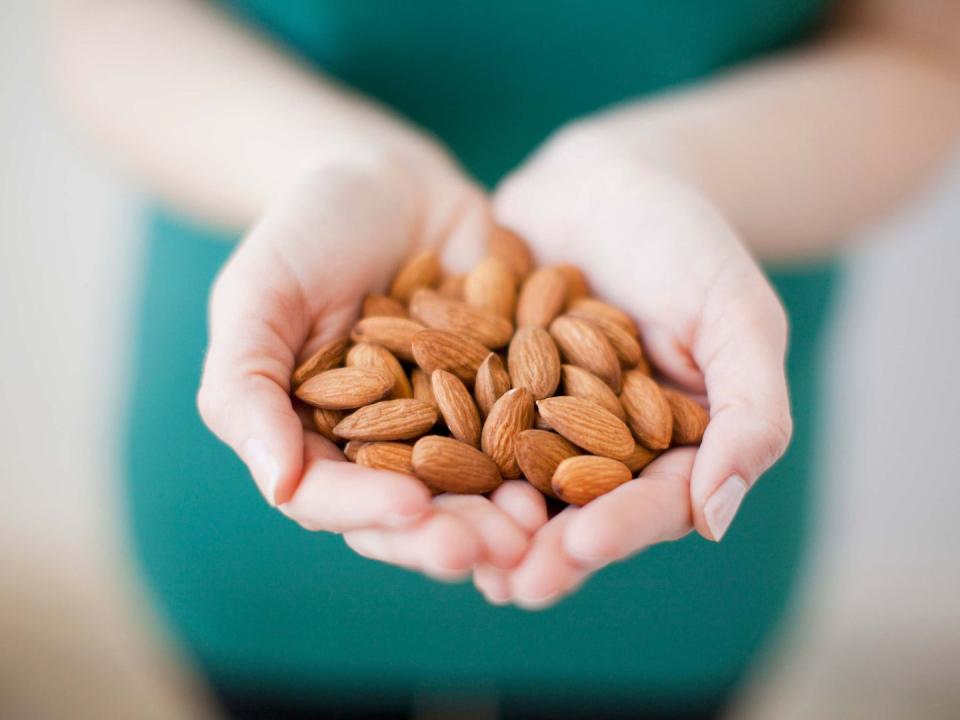 studio shot of woman showing handful of almonds