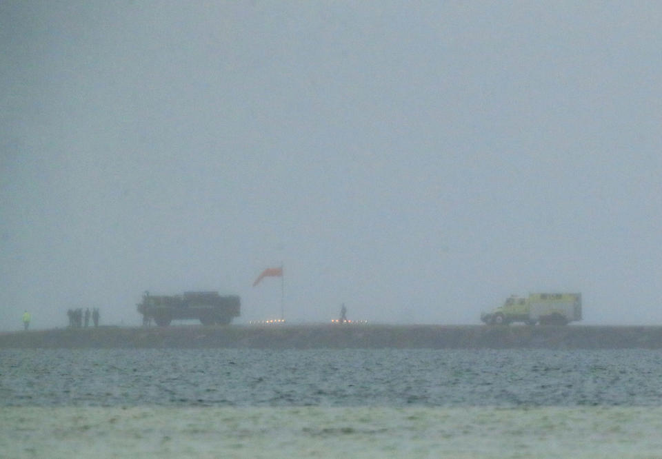 Rescue personnel are seen at the end of the runway at MCAS Kaneohe Bay after a downed U.S. Navy aircraft crashed in Kaneohe Bay, Monday, Nov. 20, 2023, in Kaneohe, Hawaii. (Jamm Aquino/Honolulu Star-Advertiser via AP)