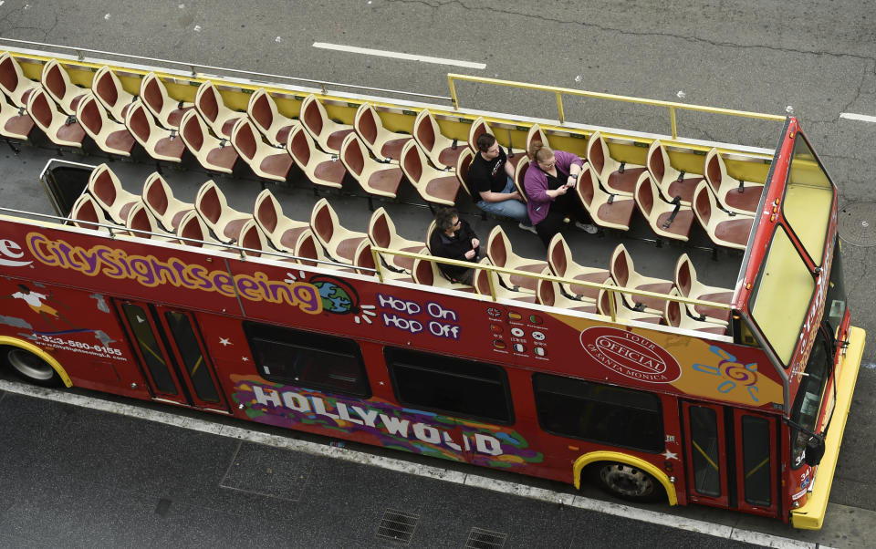 FILE - In this March 12, 2020, file photo, tourists sit in a mostly empty sightseeing bus on Hollywood Boulevard in the Hollywood section of Los Angeles. Los Angeles and San Francisco are poised Tuesday, May 4, 2021, to be the only major urban areas in the state to meet guidelines to move into the least-restrictive tier. (AP Photo/Chris Pizzello, File)