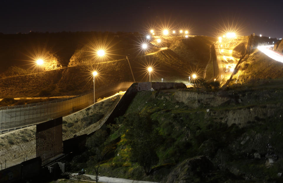 FILE - In this Jan. 7, 2019, file photo, floodlights from the U.S, illuminate multiple border walls Monday, Jan. 7, 2019, seen from Tijuana, Mexico. Congress has only a few weeks to advance an emergency funding bill to deal with the escalating humanitarian crisis at the southern border, creating a time crunch that has lawmakers on all sides alarmed. (AP Photo/Gregory Bull, File)