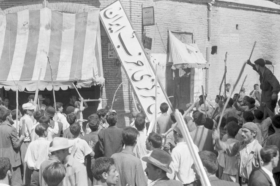 ARCHIVO - Una multitud derriba el letrero del Partido Irán de su sede en Teherán, el 19 de agosto de 1953, durante un golpe de Estado que derribó al primer ministro Mohammad Mossadegh y su gobierno. (AP Foto, archivo)