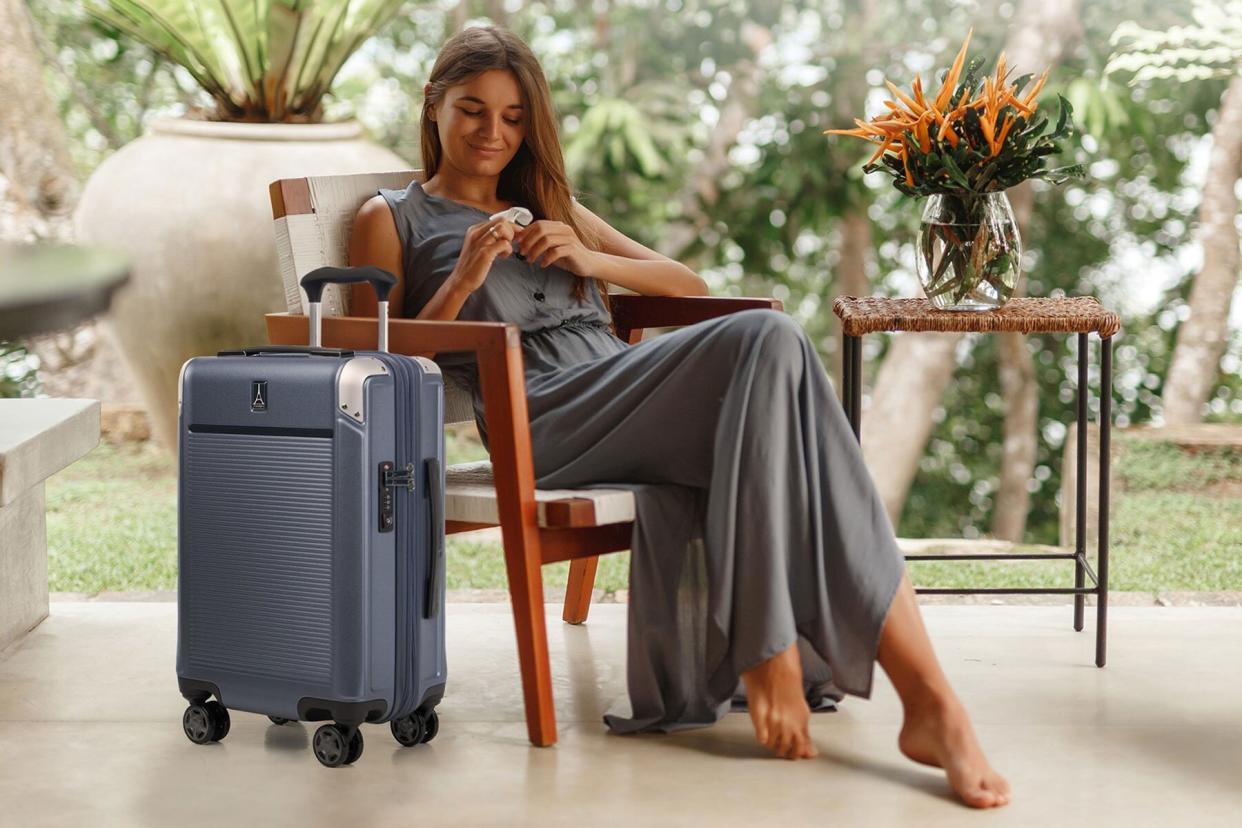 Woman sitting next to light blue hardside luggage