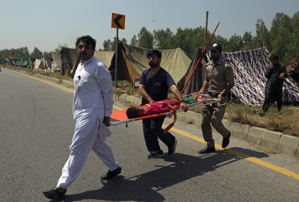 FILE - Pakistani health workers carry a sick girl who fled her flood-hit home, in Charsadda, Pakistan, Aug. 29, 2022. The flooding has all the hallmarks of a catastrophe juiced by climate change, but it is too early to formally assign blame to global warming, several scientists tell The Associated Press. (AP Photo/Mohammad Sajjad, File)