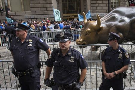 New York City police officers stand guard in front of the Charging Bull sculpture as hundreds of protesters take part in the Flood Wall Street demonstration in Lower Manhattan, New York September 22, 2014. REUTERS/Adrees Latif