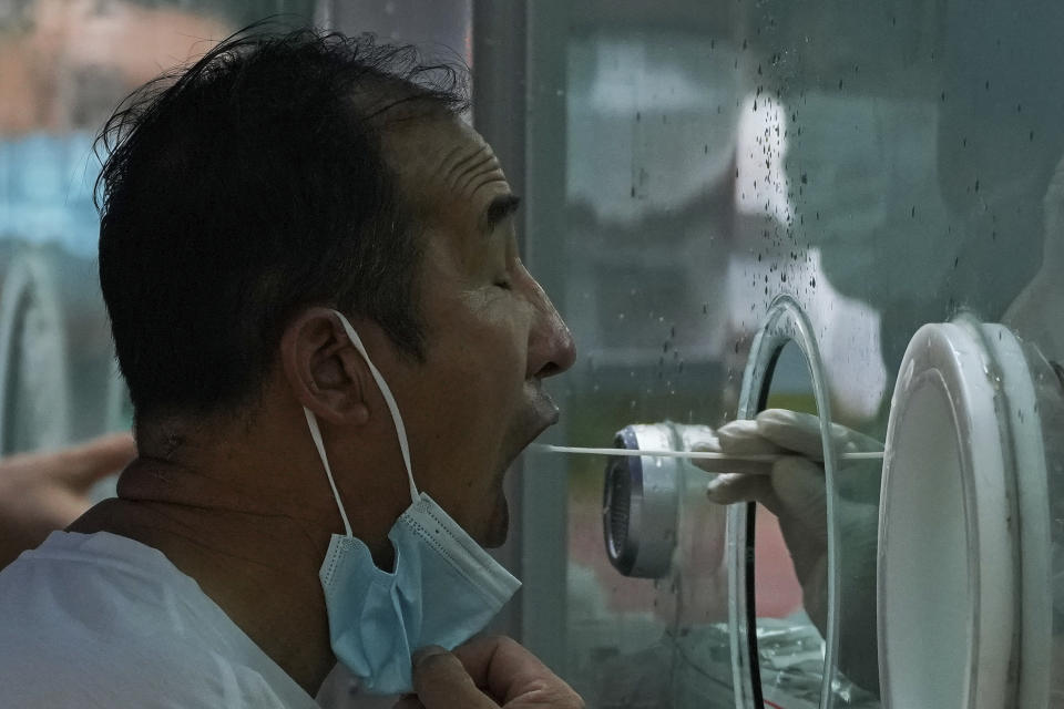 A man pulls his mask to get his routine COVID-19 throat swab at a coronavirus testing site in Beijing, Tuesday, Aug. 9, 2022. Chinese authorities have closed Tibet's famed Potala Palace after a minor outbreak of COVID-19 was reported in the Himalayan region. (AP Photo/Andy Wong)