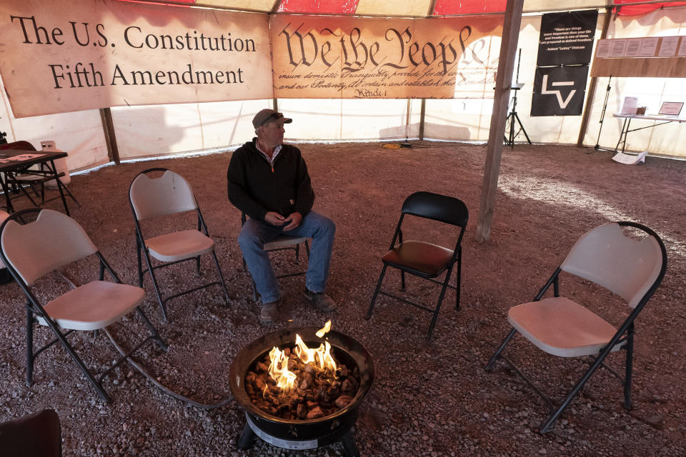 Danny Nielsen sits around a gas fire on property he purchased next to the head gates of the Klamath River on Wednesday, June 9, 2021, in Klamath Falls, Ore. Nielsen, who owns 43 acres in the Klamath Project, is among those who have threatened to forcibly open the head gates of the Upper Klamath Lake if the U.S. Bureau of Reclamation does not release water for downstream users. (AP Photo/Nathan Howard)