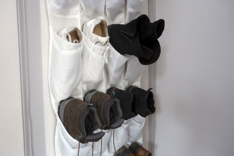 Shoe rack hanging on a wooden door, storage for shoes close-up