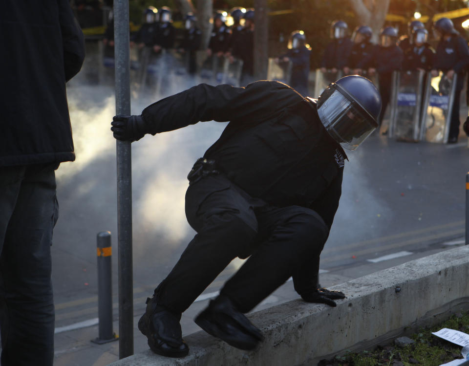 A riot police runs after a firework explodes, thrown by a protestor outside of the Parliament during a strike to protest government plans to privatize the state-run organization in Nicosia, Cyprus, Thursday, Feb. 27, 2014. Hundreds of protesters have gathered outside Cyprus' parliament to voice opposition against legislation that will pave the way for the privatization of state-owned companies. (AP Photo/Petros Karadjias)