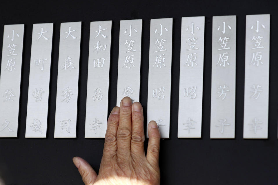 A mourner touches a name plate of a victim in the 2011 earthquake and tsunami, at Kamaishi Memorial Park in Kamaishi, Iwate prefecture, Japan Thursday, March 11, 2021. Thursday marks the 10th anniversary of the massive earthquake, tsunami and nuclear disaster that struck Japan's northeastern coast. (Takaki Yajima/Kyodo News via AP)