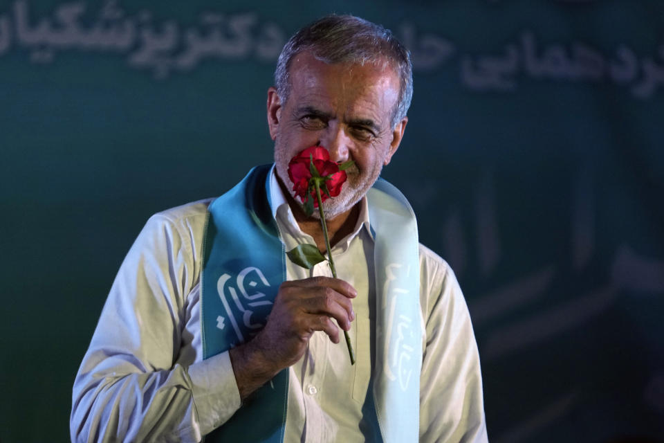 Reformist candidate for the Iran's presidential election Masoud Pezeshkian smells a flower during a campaign rally in Tehran, Iran, Wednesday, July 3, 2024. Comments suggesting that Iran's reformist presidential candidate could increase government-set gasoline prices have raised fears of a repeat of nationwide protests. (AP Photo/Vahid Salemi)