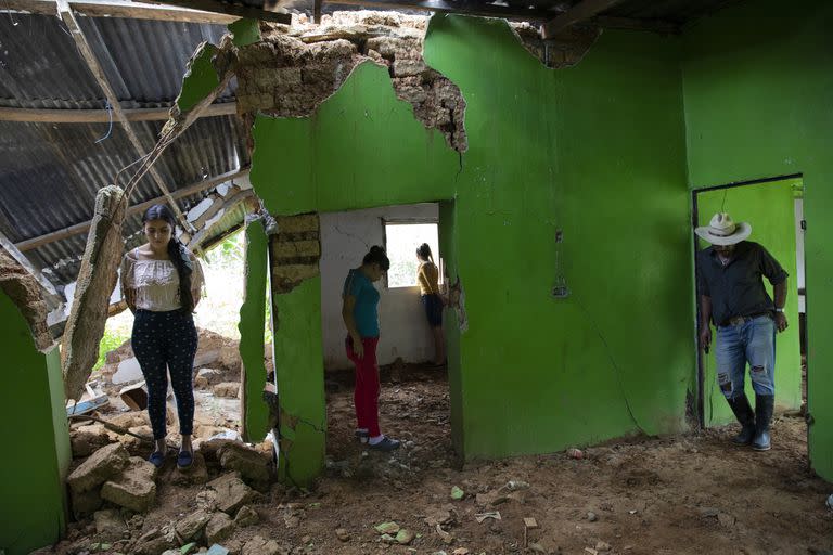 Marian Castron, 23; Maria Castron, 25; Jenny Castron, de 19 años, y Omar Castron, de 50, visitan su casa devastada por un deslizamiento de tierra.