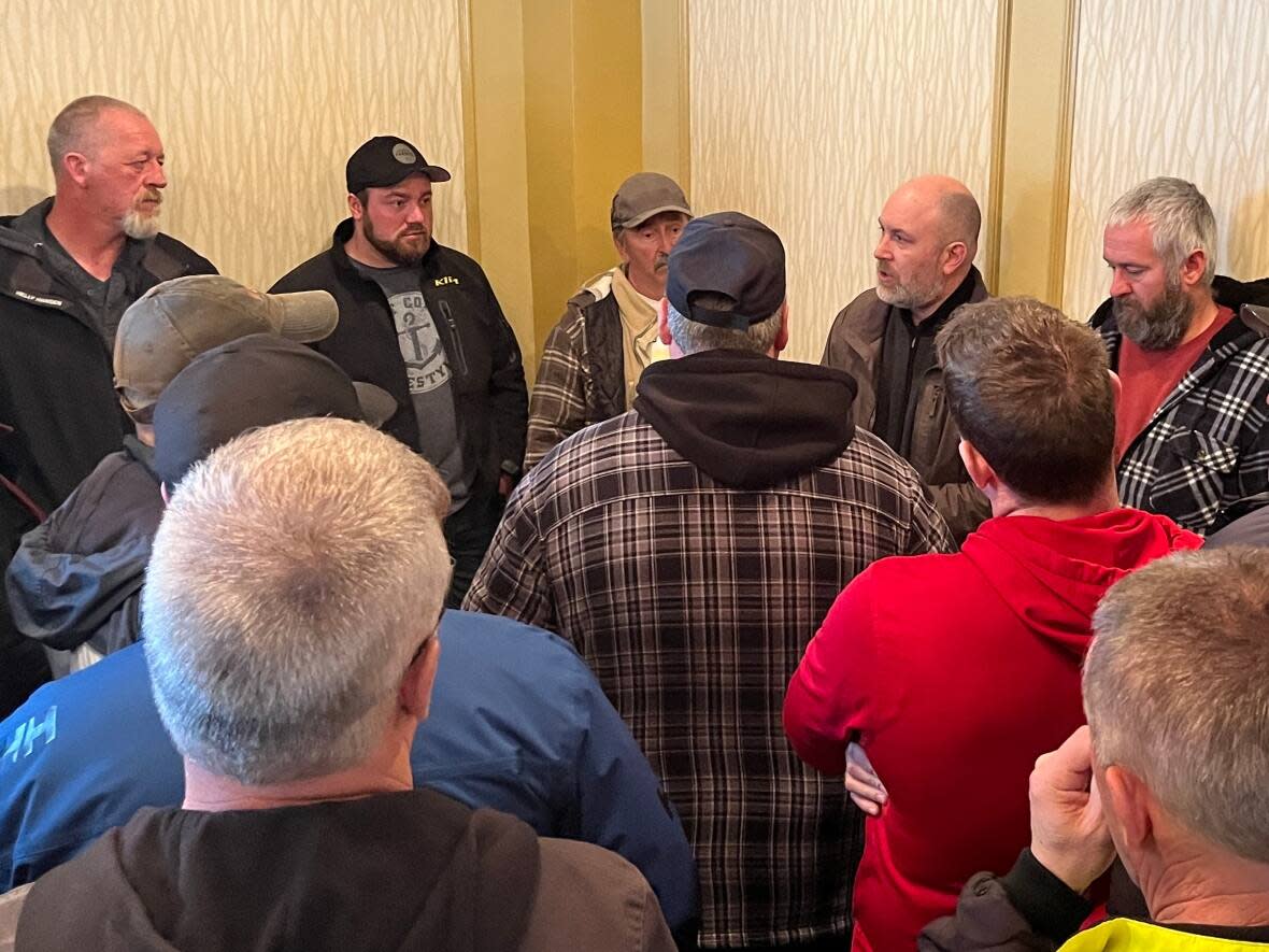 Fisheries union executive Jason Spingle, centre, consults with crab harvesters about next steps following a heated meeting in St. John's on Friday. (Terry Roberts/CBC - image credit)