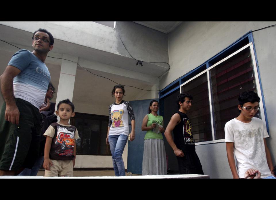 In this photo taken June 28, 2012, asylum seekers, from left to right, Saad Abdul Azm and his son Leis from Iraq, Soudeh Mohammadpour, Mehran Mohammadpour and Zoleikha Golpur from Iran and Mojtada Bahadori from Afghanistan stand outside their temporary home in Cisarua, West Java, Indonesia. (AP Photo/Achmad Ibrahim)