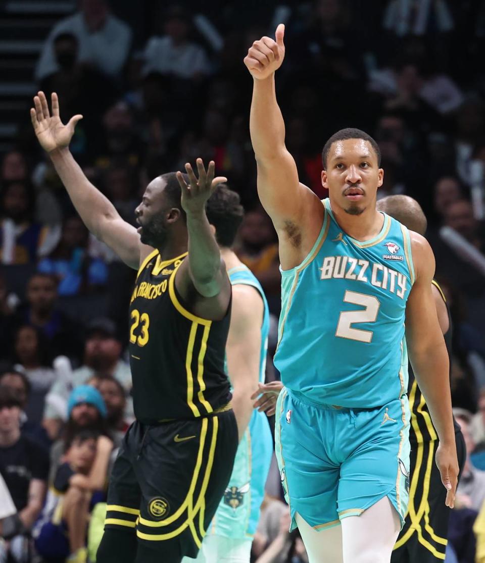 Charlotte Hornets forward Grant Williams, right, lifts his hand in the air as he celebrates drawing a foul on Golden State Warriors forward Draymond Green, left, during second-half action at Spectrum Center in Charlotte, NC on Friday, March 29, 2024. The Warriors defeated the Hornets 115-97.