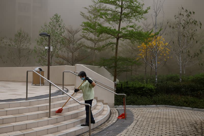 A cleaner works in smoke, as a warehouse is on fire in the city's bustling Kowloon district, in Hong Kong