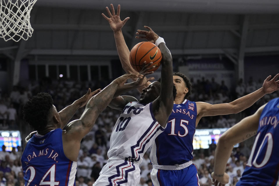 TCU guard Damion Baugh (10) attempts to shoot as Kansas forward K.J. Adams Jr. (24) and Kevin McCullar Jr. (15) defend in the second half of an NCAA college basketball game, Monday, Feb. 20, 2023, in Fort Worth, Texas. (AP Photo/Tony Gutierrez)