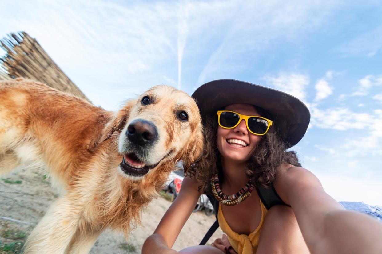 woman taking a self with her dog on a beach