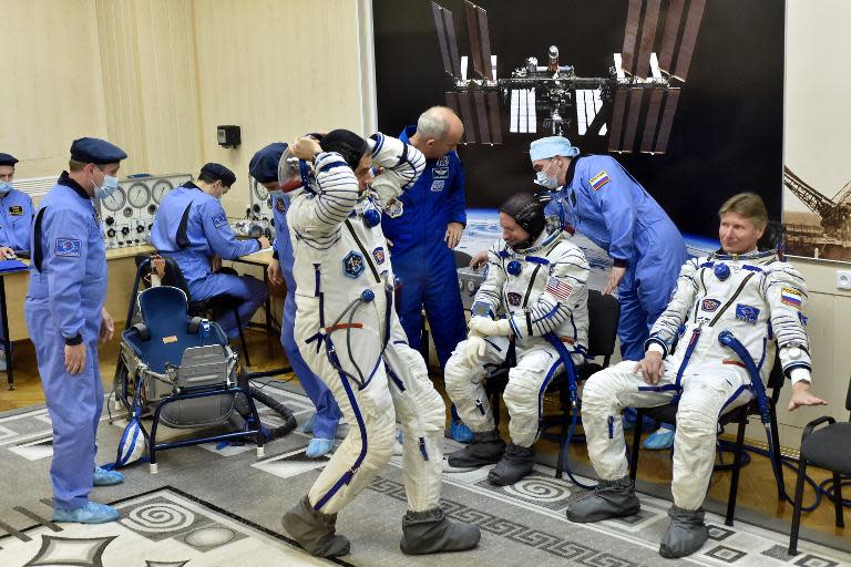 Russian cosmonaut Mikhail Kornienko (C) has his space suit tested as US astronaut Scott Kelly (3rdR) and Russian cosmonaut Gennady Padalka (R) wait at Baikonur cosmodrome, prior to blasting off for the International Space Station, on March 27, 2015