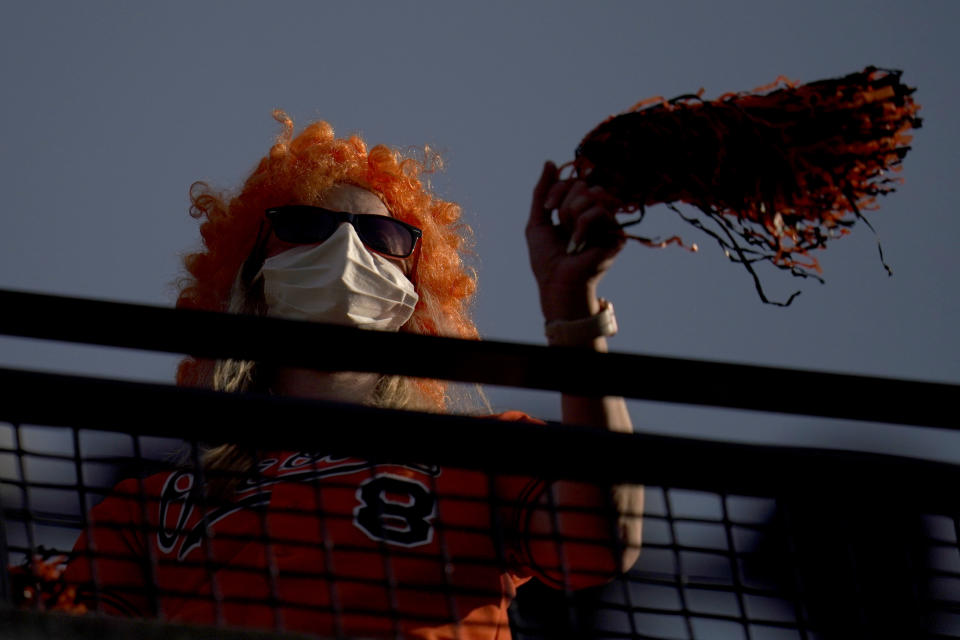 A fan waves pompons during the sixth inning of a baseball game between the Baltimore Orioles and the Boston Red Sox, Thursday, April 8, 2021, on Opening Day in Baltimore. (AP Photo/Julio Cortez)