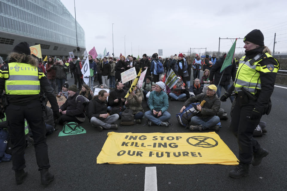 Police officers speak with climate activists block the main highway around Amsterdam near the former headquarters of a ING bank to protest its financing of fossil fuels, Saturday, Dec. 30, 2023. Protestors walked onto the road at midday, snarling traffic around the Dutch capital in the latest road blockade organized by the Dutch branch of Extinction Rebellion. (AP Photo/Patrick Post)