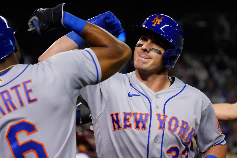 New York Mets' James McCann (33) high fives Starling Marte (6) after hitting a two run home run during the seventh inning of a baseball game against the Arizona Diamondbacks, Friday, April 22, 2022, in Phoenix. (AP Photo/Matt York)