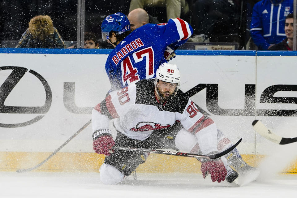 New Jersey Devils' Tomas Tatar (90) and New York Rangers' Morgan Barron (47) fight for position during the second period of an NHL hockey game Friday, March 4, 2022, in New York. (AP Photo/Frank Franklin II)